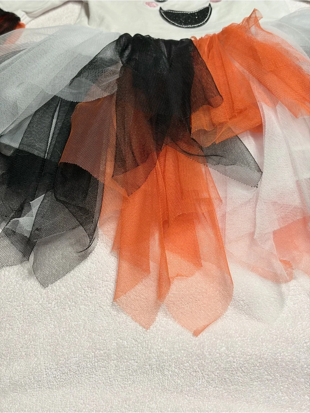 Cutie Halloween costume Has orange, black, and white tulle skirt and wrists.
